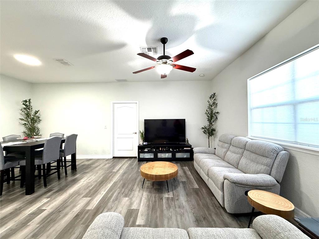 A living room features gray wood-look flooring, a ceiling fan, and a light gray sofa — 17411 PROMENADE DRIVE, CLERMONT, FL