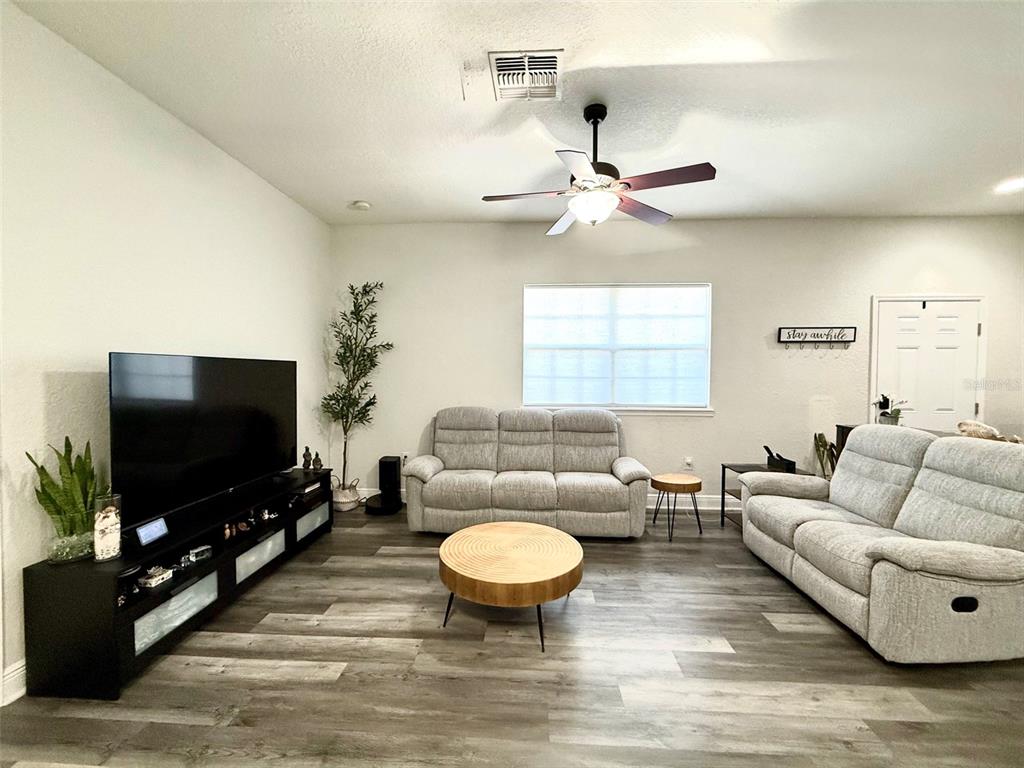 A living room features light gray sofas, a wood coffee table, and a black media console — 17411 PROMENADE DRIVE, CLERMONT, FL
