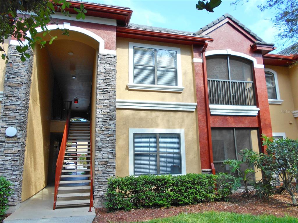 An exterior view of a two-story apartment building with stone pillars and a staircase — 2171 PORTOFINO PLACE UNIT 2727, PALM HARBOR, FL
