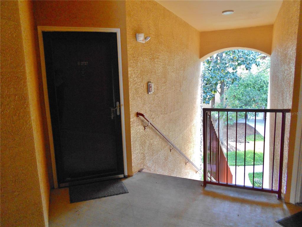 A dark front door opens onto a concrete landing with a metal railing and stairs — 2171 PORTOFINO PLACE UNIT 2727, PALM HARBOR, FL
