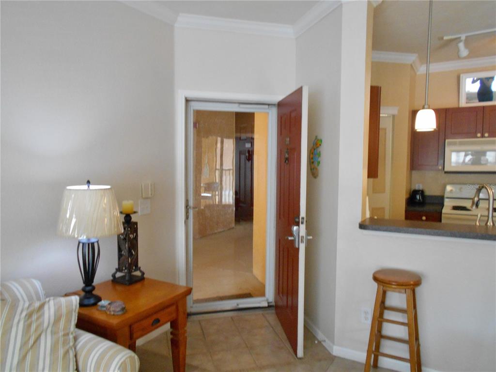 An interior view showing an entryway with a red door, a side table, and kitchen — 2171 PORTOFINO PLACE UNIT 2727, PALM HARBOR, FL