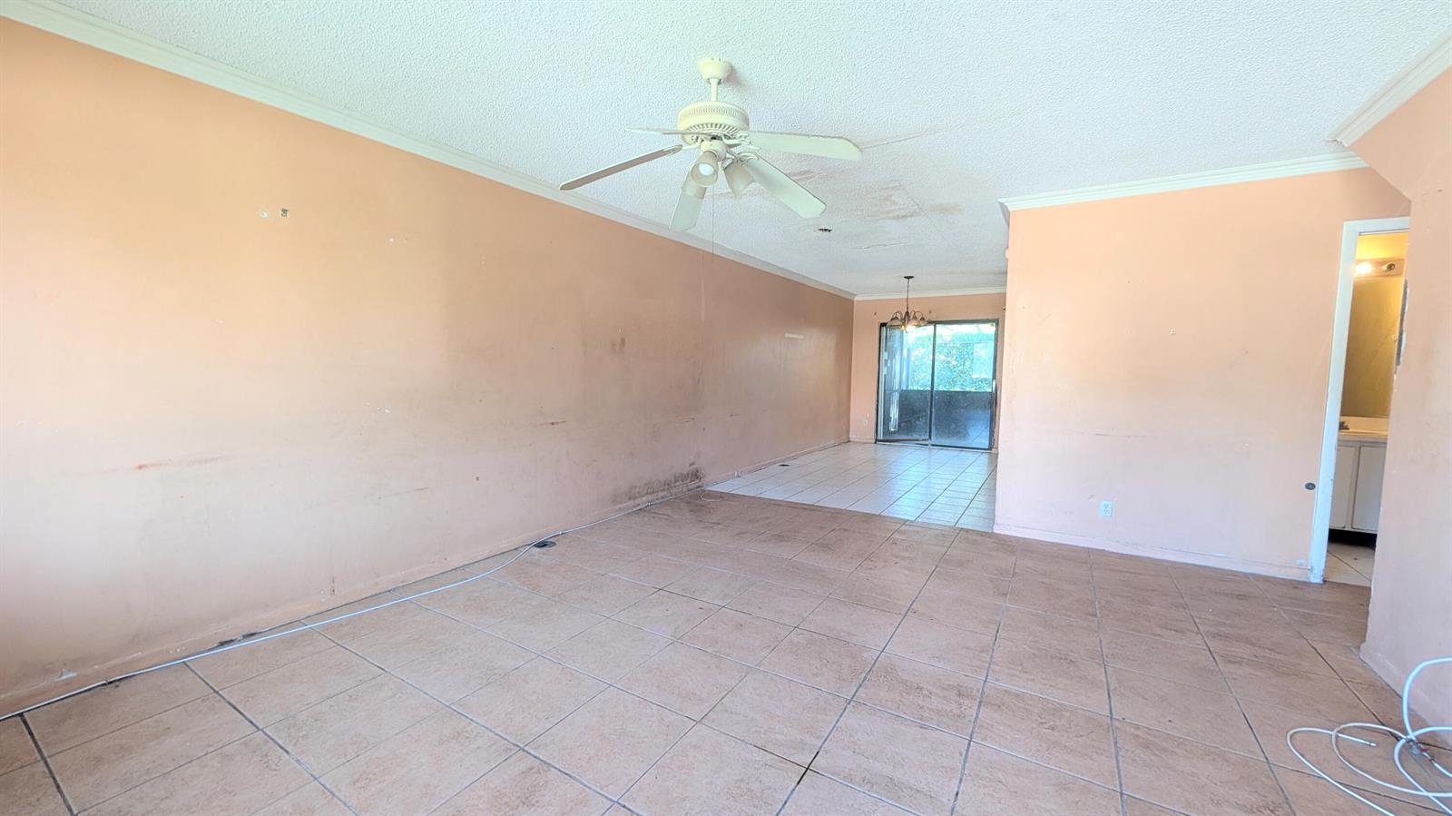 An empty living room with peach-colored walls, tile flooring, and a ceiling fan — 807 Riverside Drive # 7, FL 33463, FL
