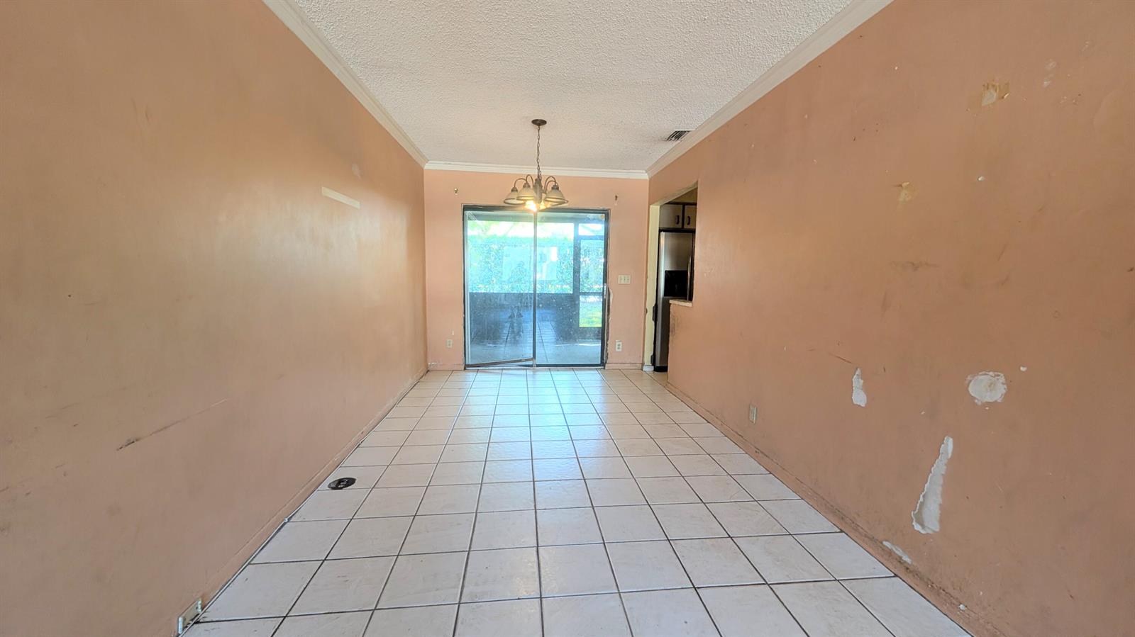 An empty dining room features peach-colored walls, white tile flooring, and a sliding glass door — 807 Riverside Drive # 7, FL 33463, FL