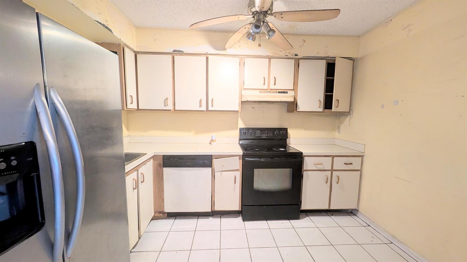 A kitchen features white cabinets, black appliances, a ceiling fan, and white tiled flooring — 807 Riverside Drive # 7, FL 33463, FL