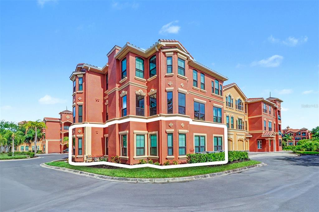 A three-story, terracotta-colored apartment building with a highlighted ground-floor unit — 2746 VIA TIVOLI UNIT 110B, CLEARWATER, FL
