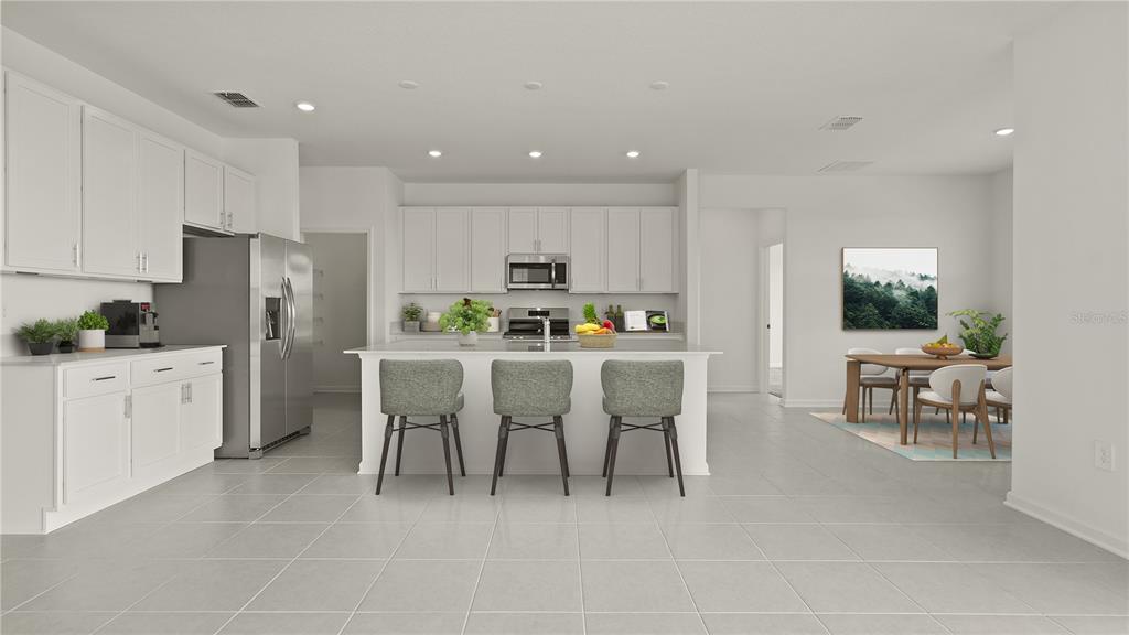 A modern kitchen features white cabinetry, a central island with three stools, and tile flooring — 3180 NAMASTE DRIVE, CLERMONT, FL
