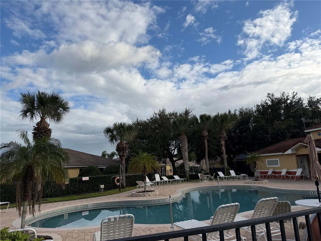 A swimming pool with lounge chairs and palm trees sits in a residential backyard — 353 PORT PLEASANT DRIVE UNIT 353, KISSIMMEE, FL
