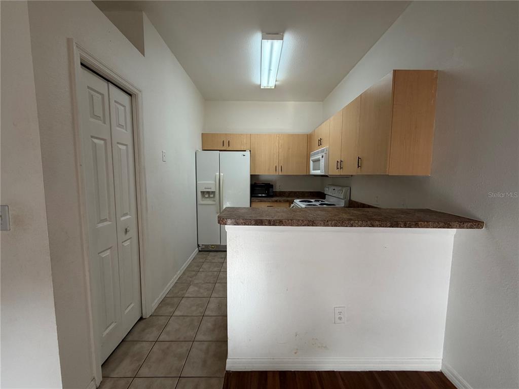A kitchen features light wood cabinets, a white refrigerator, and a breakfast bar counter — 353 PORT PLEASANT DRIVE UNIT 353, KISSIMMEE, FL
