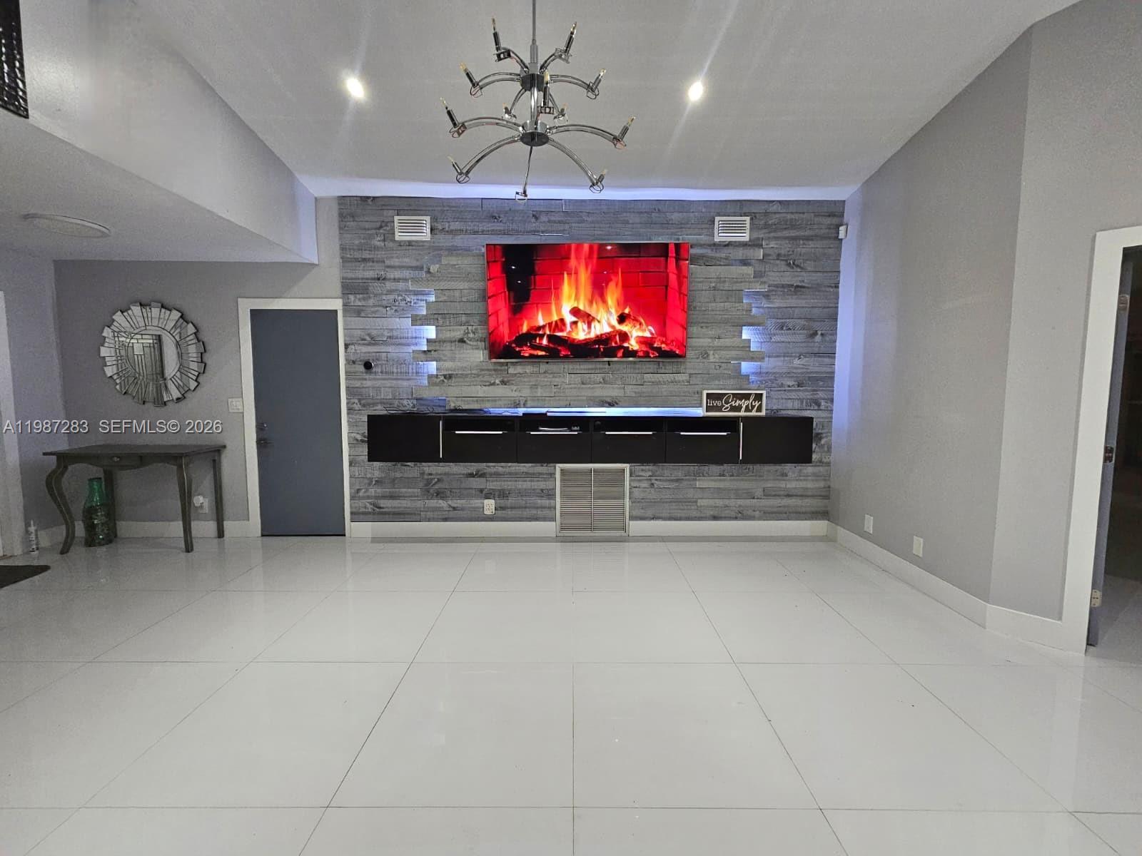A living room features a wall-mounted television, a floating console, and a wood-paneled accent wall — 8003 SW 158th Pl, Miami FL 33193, MIAMI, FL