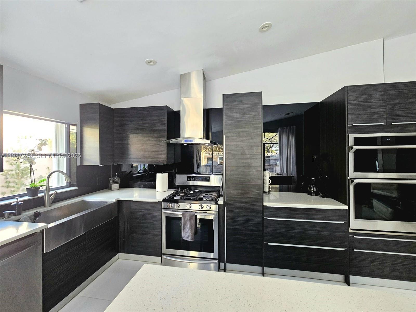 A modern kitchen features dark wood cabinetry, stainless steel appliances, and white quartz countertops — 8003 SW 158th Pl, Miami FL 33193, MIAMI, FL