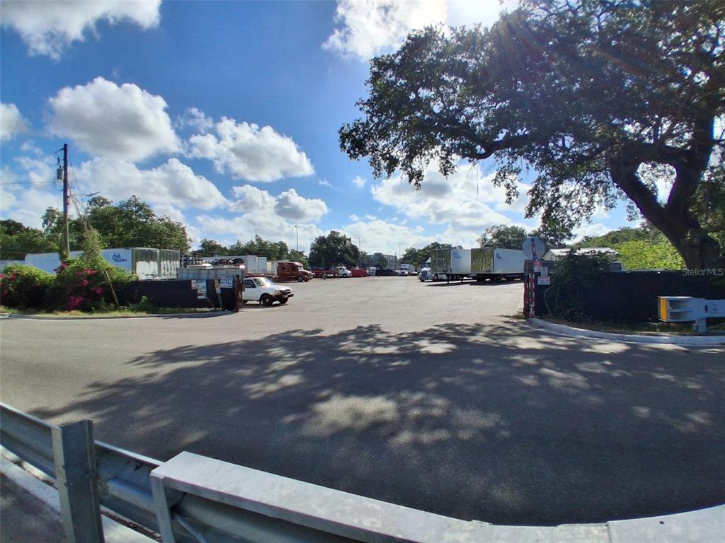 An outdoor paved lot contains several parked semi-truck trailers and a white pickup truck — 7001 CAUSEWAY BOULEVARD, TAMPA, FL