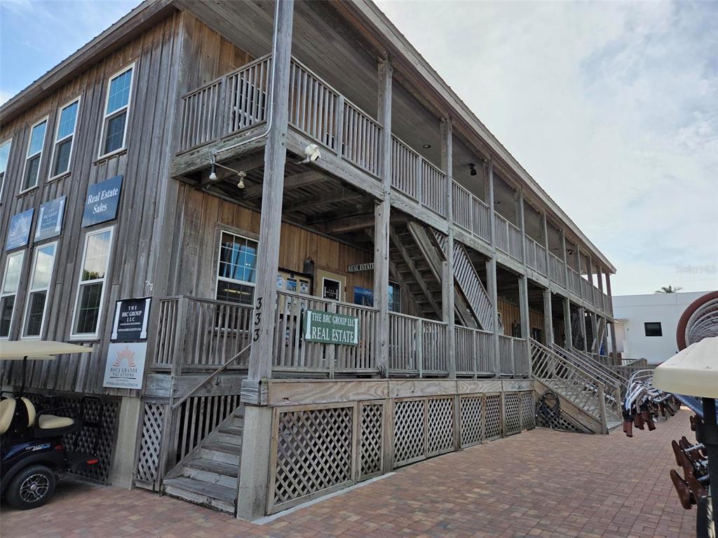 A two-story wooden building with exterior staircases and balconies sits on a brick-paved lot — 333 PARK AVENUE UNIT 2A, BOCA GRANDE, FL