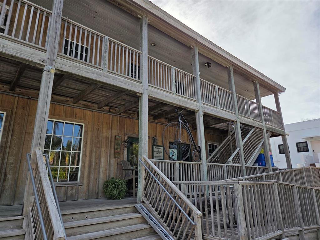 A two-story wooden building features a large front porch, exterior staircases, and a vintage bicycle — 333 PARK AVENUE UNIT 2A, BOCA GRANDE, FL