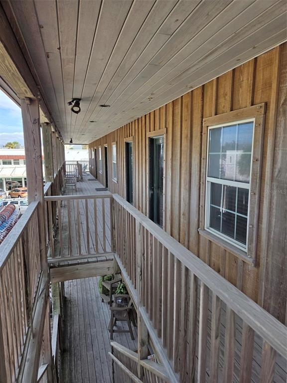 An exterior wooden walkway with railings runs along the side of a building with windows — 333 PARK AVENUE UNIT 2A, BOCA GRANDE, FL