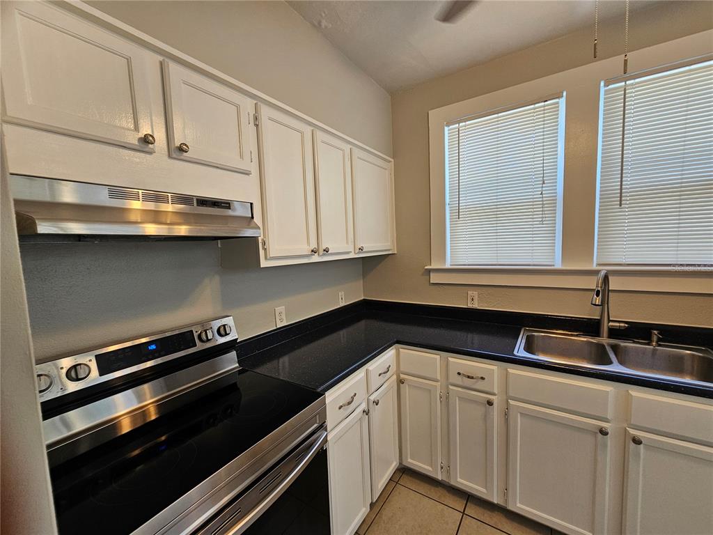 A kitchen features white cabinets, black countertops, a stainless steel stove, and two windows — 1408 N FORT HARRISON AVENUE UNIT B, CLEARWATER, FL