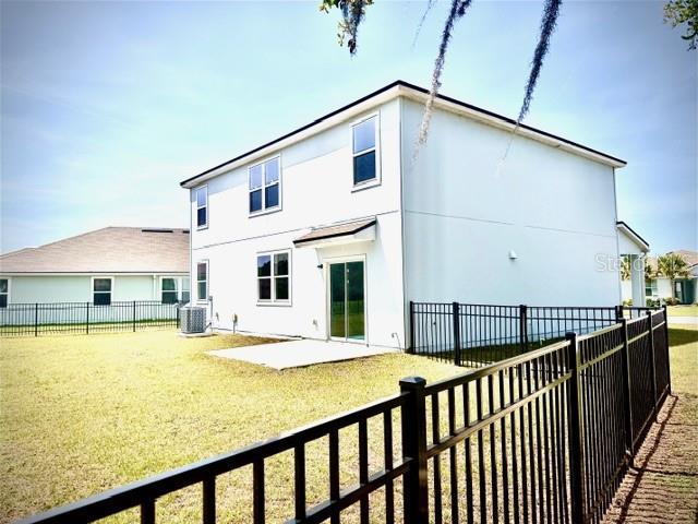 The exterior of a two-story light-colored house features a fenced backyard and a sliding door — 449 JARAMA CIRCLE, ST AUGUSTINE, FL