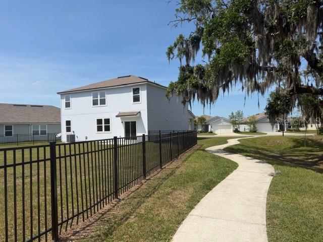 A two-story house with a black metal fence and a sidewalk in the foreground — 449 JARAMA CIRCLE, ST AUGUSTINE, FL