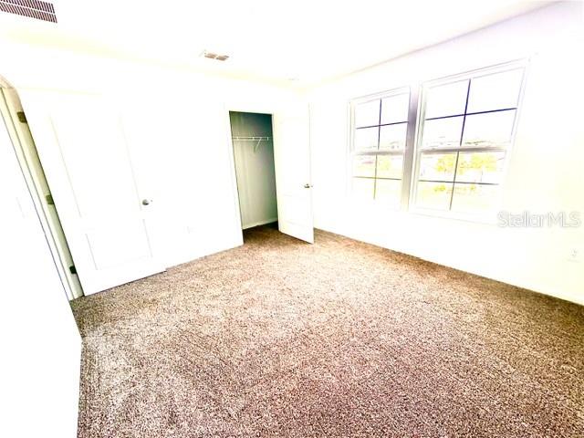 An empty bedroom features beige carpet, white walls, a closet, and two windows — 449 JARAMA CIRCLE, ST AUGUSTINE, FL