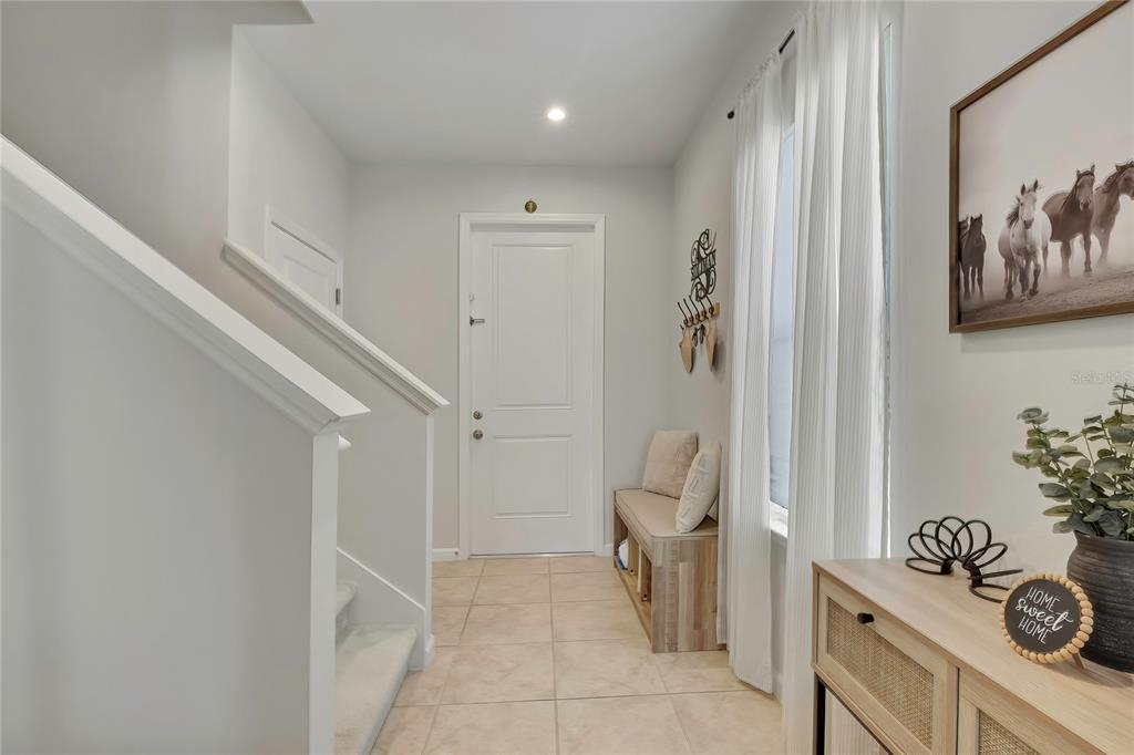 An entryway features a tiled floor, a staircase, a wooden bench, and a front door — 11912 THORNCREST DRIVE, SPRING HILL, FL