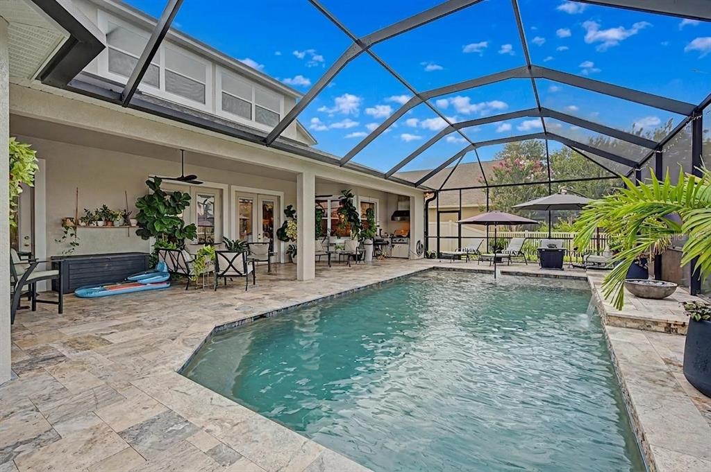 A screened-in patio features a swimming pool, stone tile flooring, and outdoor seating areas — 3038 MARBLE CREST DRIVE, LAND O LAKES, FL