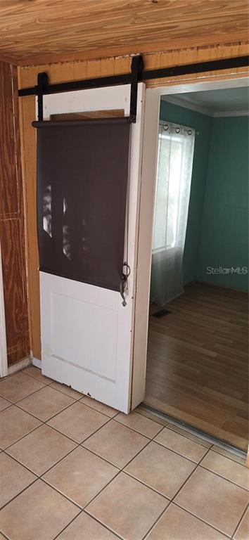 A white sliding barn door with a dark roller shade hangs in a tiled entryway — 315 VIRGINA ST, FROSTPROOF, FL