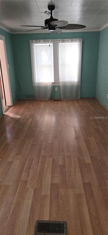 An empty room with teal walls, wood-look flooring, a ceiling fan, and a double window — 315 VIRGINA ST, FROSTPROOF, FL