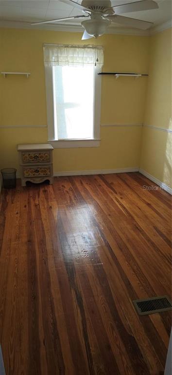A bedroom with yellow walls, hardwood floors, a ceiling fan, and a single window — 315 VIRGINA ST, FROSTPROOF, FL