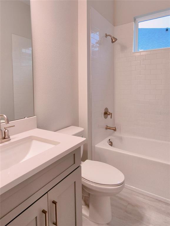 A bathroom features a gray vanity, a white toilet, and a tub-shower with subway tile — 5659 NEVIS TERRACE, KISSIMMEE, FL