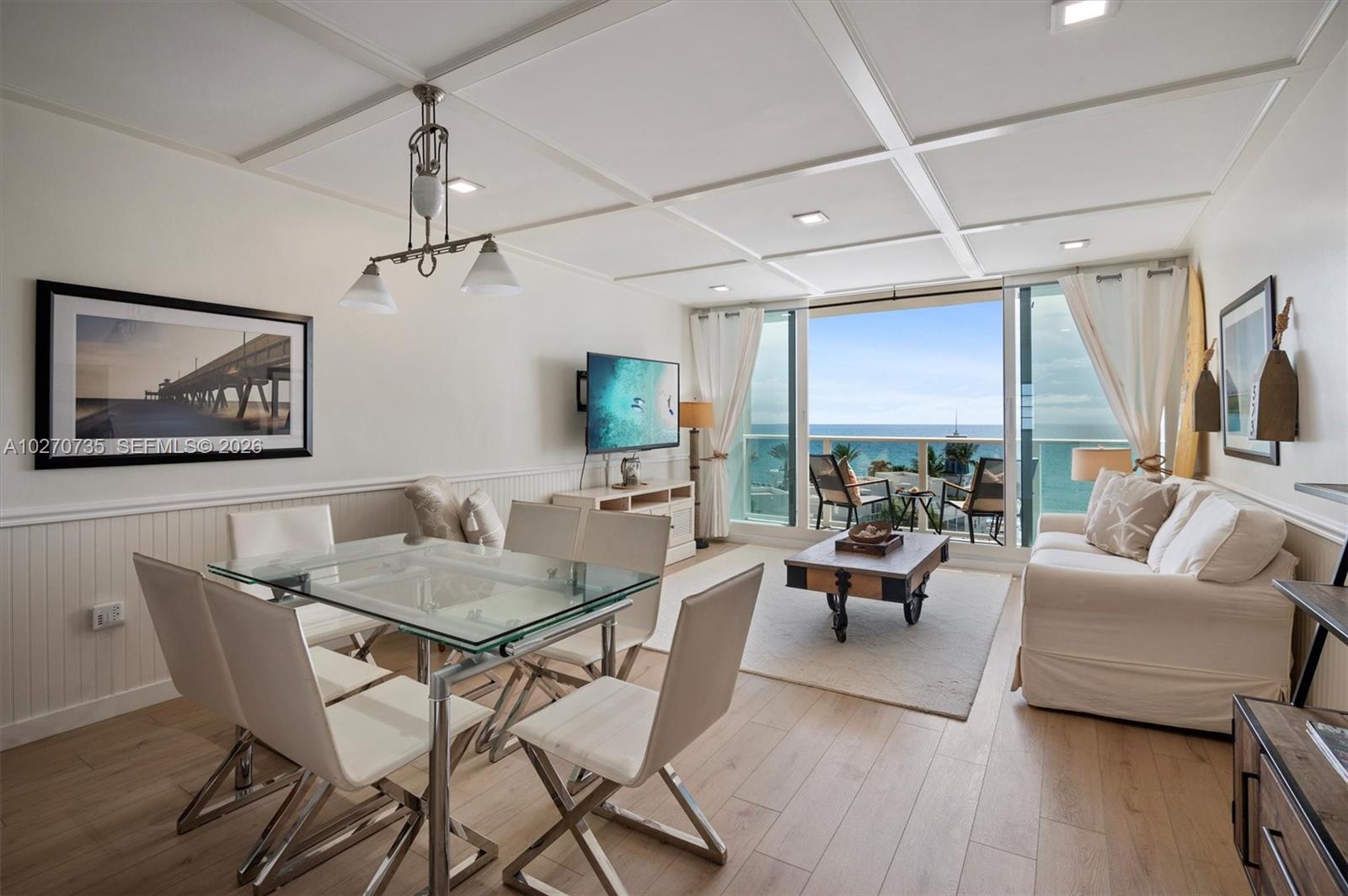 A bright living and dining area features a glass table, white sofa, and ocean view balcony — 3505 S OCEAN DR # 607, Hollywood FL 33019, HOLLYWOOD, FL