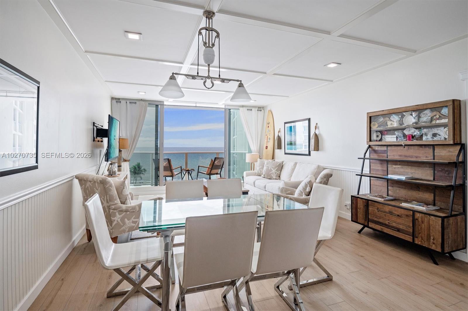 A dining and living area features a glass table, white chairs, and a balcony view — 3505 S OCEAN DR # 607, Hollywood FL 33019, HOLLYWOOD, FL