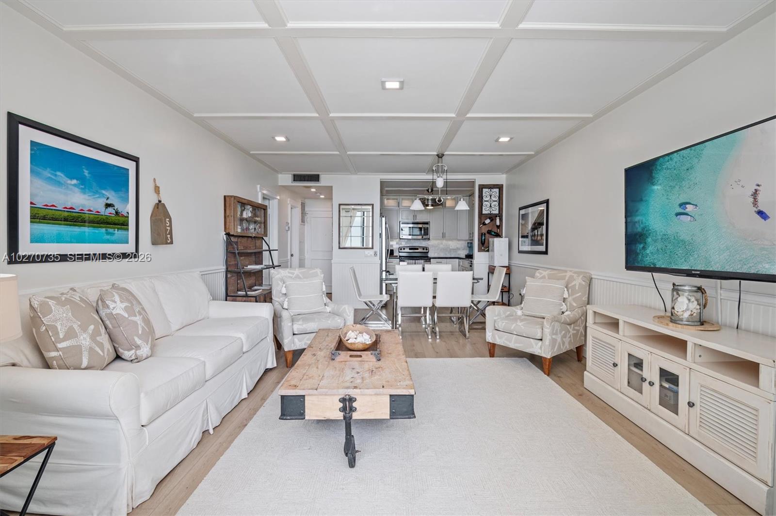 A living room features a white sofa, coffee table, armchairs, and a coffered ceiling — 3505 S OCEAN DR # 607, Hollywood FL 33019, HOLLYWOOD, FL
