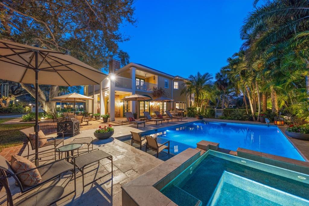 A backyard features a swimming pool, a hot tub, patio furniture, and a two-story house — 100 SARASOTA ROAD, BELLEAIR, FL