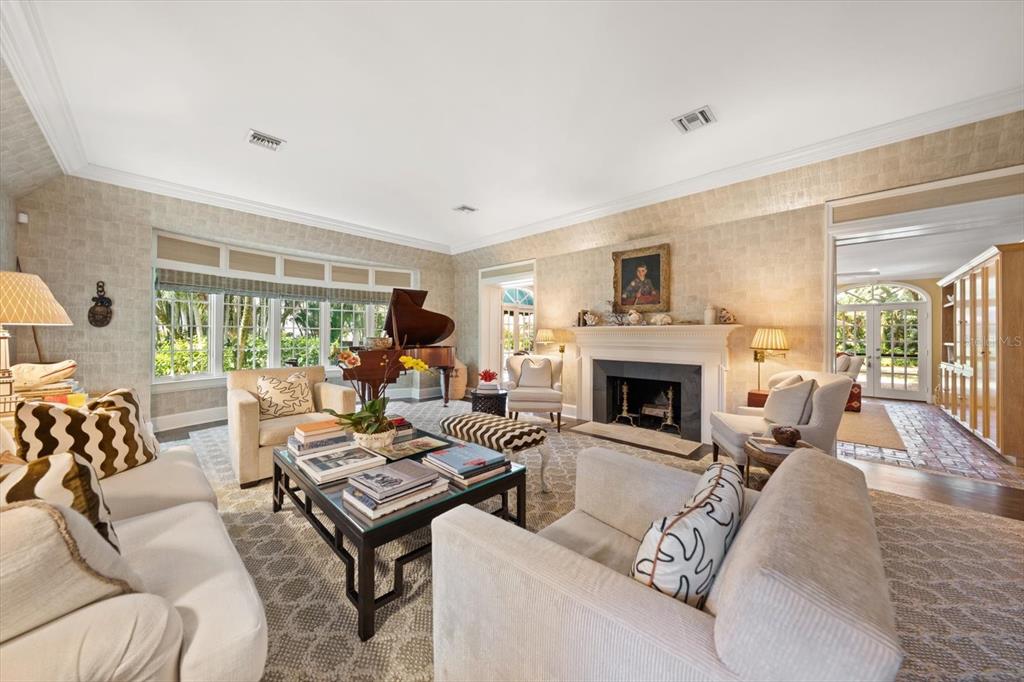 A living room features a fireplace, a grand piano, and neutral furniture on a rug — 100 SARASOTA ROAD, BELLEAIR, FL
