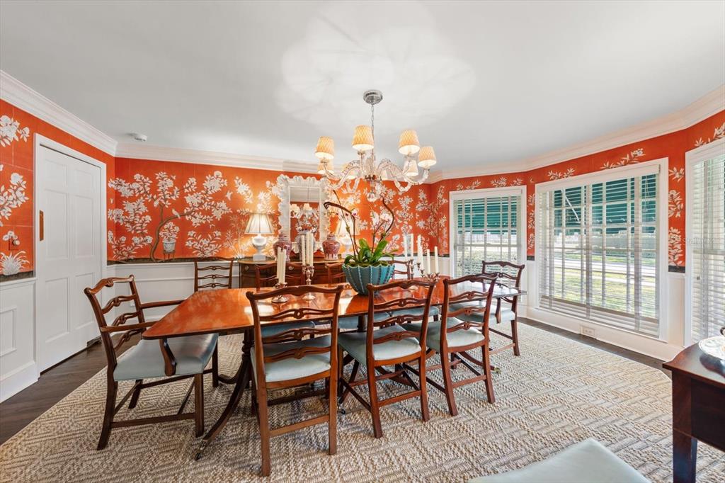 A dining room features orange floral wallpaper, a wooden table with chairs, and a chandelier — 100 SARASOTA ROAD, BELLEAIR, FL
