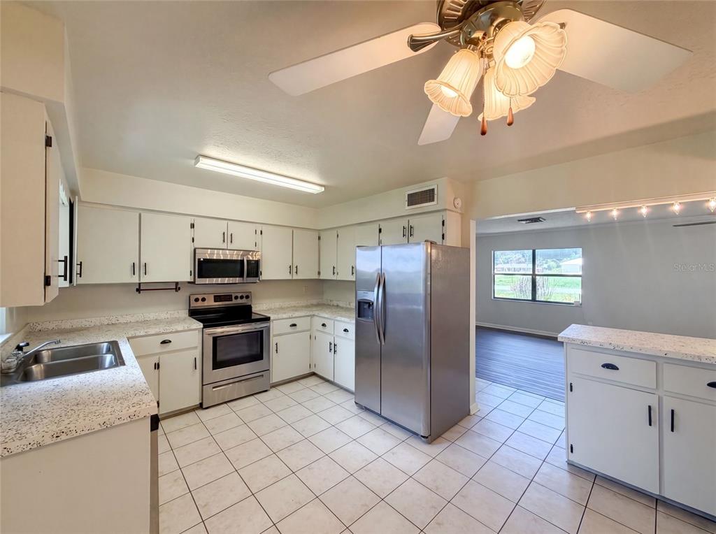 A kitchen with white cabinets, stainless steel appliances, speckled countertops, and tile flooring — 3129 AVENUE W NW, WINTER HAVEN, FL