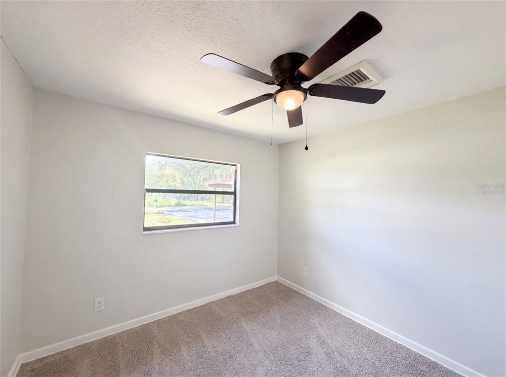 A bedroom features light gray walls, beige carpet, a ceiling fan, and a single window — 3129 AVENUE W NW, WINTER HAVEN, FL