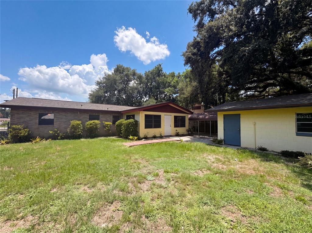 The exterior of a single-story home with a brick and yellow siding facade — 3129 AVENUE W NW, WINTER HAVEN, FL