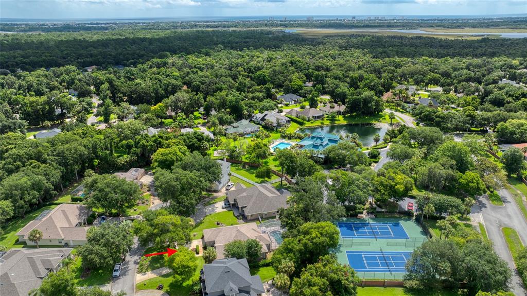 An aerial view shows a residential neighborhood with houses, trees, a pond, and tennis courts — 5 WATERCLIFF LANE, ORMOND BEACH, FL