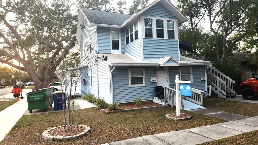 A two-story light blue house with a wheelchair ramp and a green dumpster outside — 614 OAK AVENUE, CLEARWATER, FL
