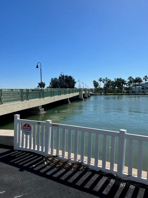 A bridge crosses a body of water with a white fence in the foreground — 285 107TH AVENUE UNIT 606, TREASURE ISLAND, FL