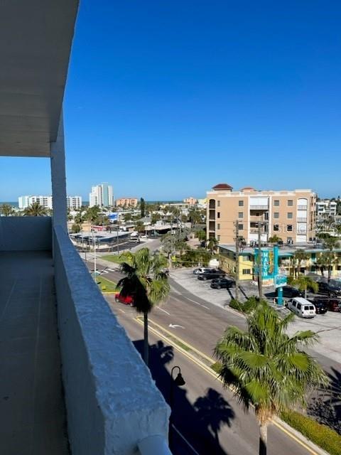 An elevated view from a balcony overlooks a street, palm trees, and nearby coastal buildings — 285 107TH AVENUE UNIT 606, TREASURE ISLAND, FL