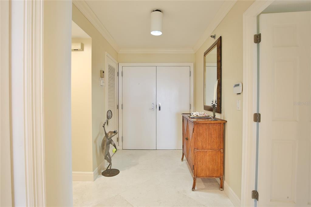 A bright entryway features light-colored tile flooring, a wooden console table, and double doors — 775 LONGBOAT CLUB ROAD UNIT 904, LONGBOAT KEY, FL