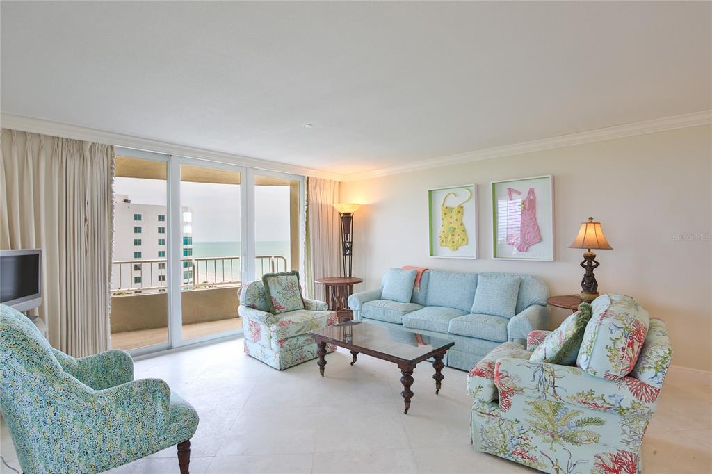 A living room features light blue furniture, patterned armchairs, and a balcony overlooking the ocean — 775 LONGBOAT CLUB ROAD UNIT 904, LONGBOAT KEY, FL