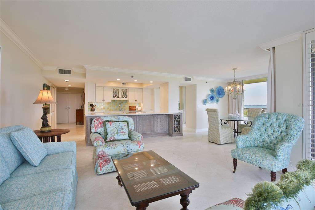 An open-concept living and dining area features light tile floors, coastal decor, and a kitchen — 775 LONGBOAT CLUB ROAD UNIT 904, LONGBOAT KEY, FL