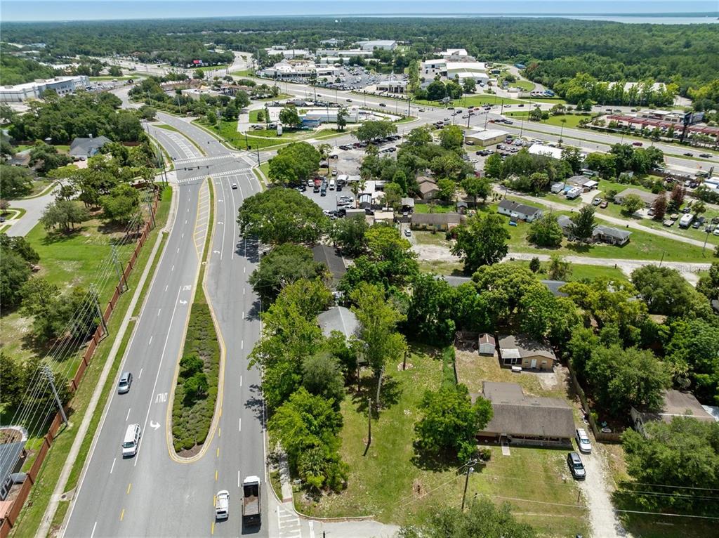 An aerial view shows a multi-lane road curving past a residential lot with trees — 3711 N RONALD REAGAN BOULEVARD, LONGWOOD, FL