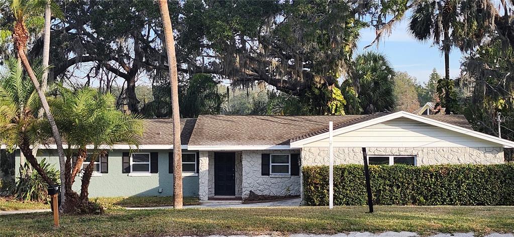 A single-story house features a light green exterior, stone accents, and a large front hedge — 3606 RIVER GROVE DRIVE, TAMPA, FL