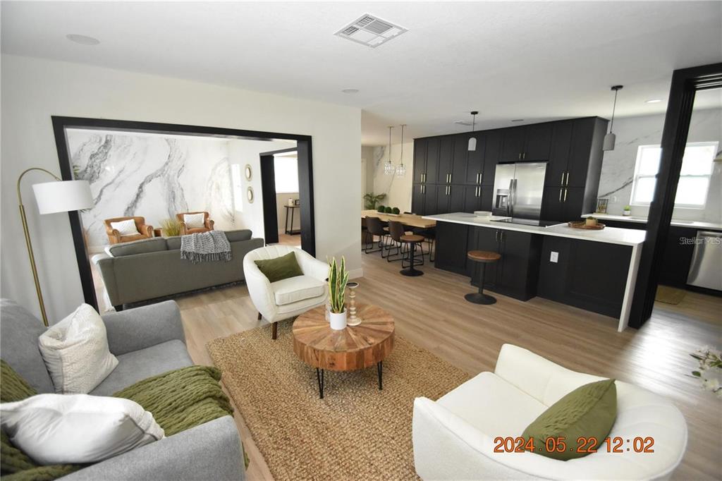 An open-concept living room and kitchen feature dark cabinetry, light wood flooring, and marble accents — 3606 RIVER GROVE DRIVE, TAMPA, FL