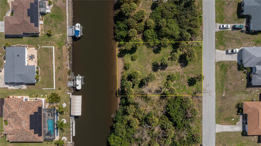 An aerial view shows a vacant rectangular lot situated between a canal and a road — 18546 ASHCROFT CIRCLE, PORT CHARLOTTE, FL