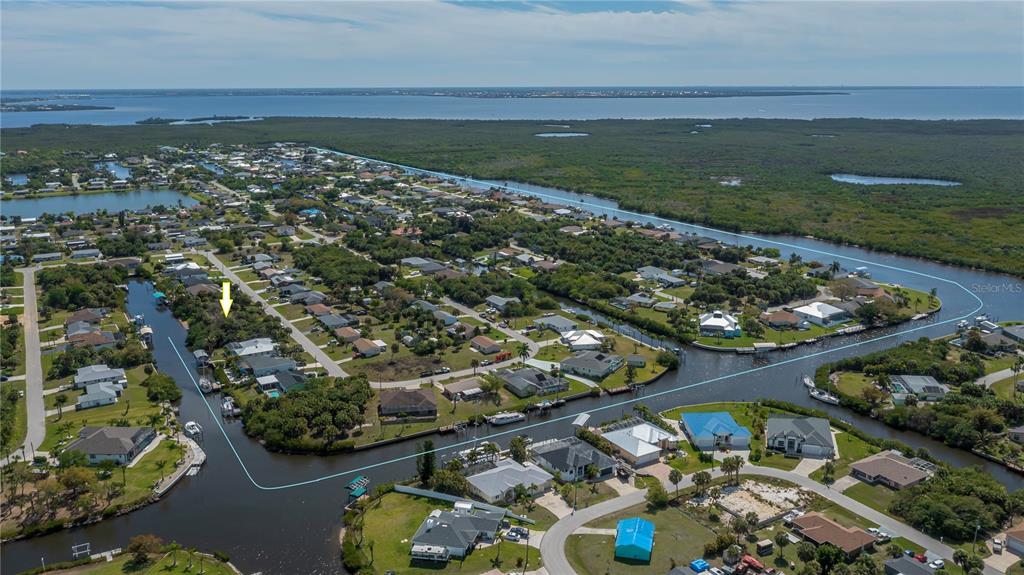 An aerial view shows a residential neighborhood with houses situated along a winding canal — 18546 ASHCROFT CIRCLE, PORT CHARLOTTE, FL