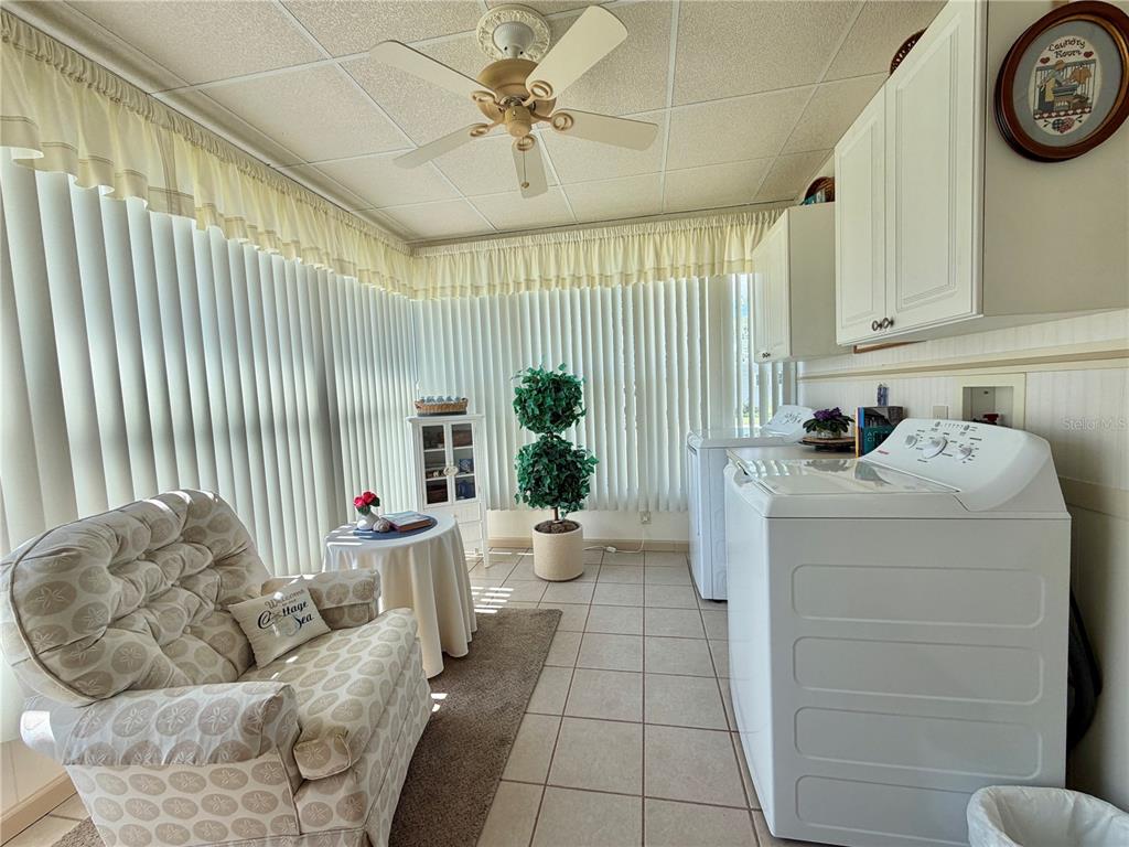 A laundry room features tile floors, a ceiling fan, vertical blinds, and a comfortable armchair — 146 HIBISCUS WAY, LEESBURG, FL